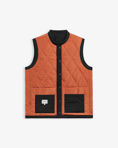 The Utility Vest in rust orange and black — front view showing quilted pattern and front pockets