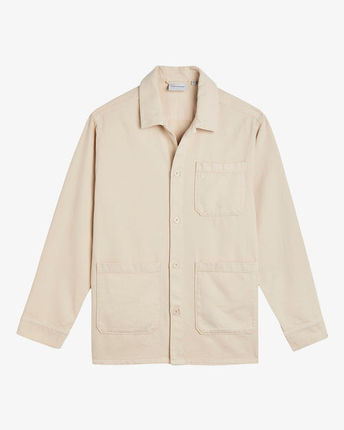 A front view of The Workwear Overshirt in cream, laid flat on a white background. The image highlights the button closures and patch pockets at the left chest and hips.