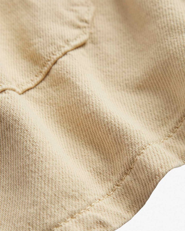 A close-up shot of the textured fabric of The Workwear Overshirt in cream, highlighting the stitching and material details.