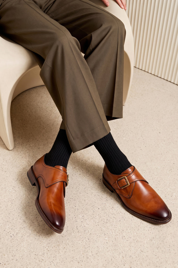 Man wearing Premium men's tan leather single monk strap dress shoes by Oswin Hyde London featuring a plain toe, adjustable golden buckle, contrast sole stitching, and a cushioned teal interior.